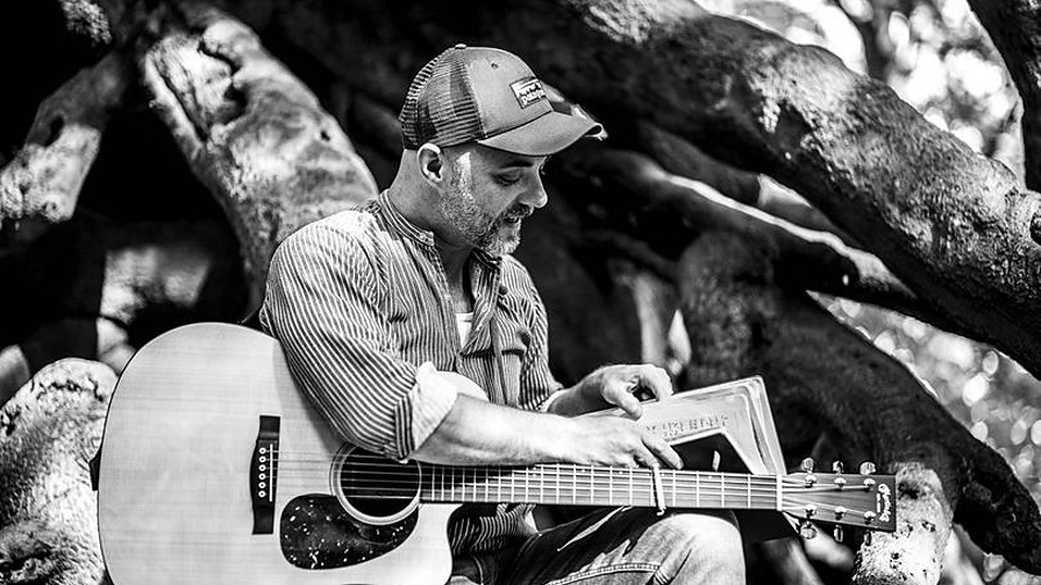 Bjoern Alberternst mit Akustikgitarre unter einem Baum